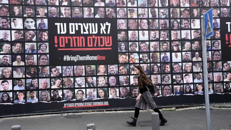 A woman in Jerusalem walks past photos of hostages held by Hamas in the Gaza Strip. Pic: AP
