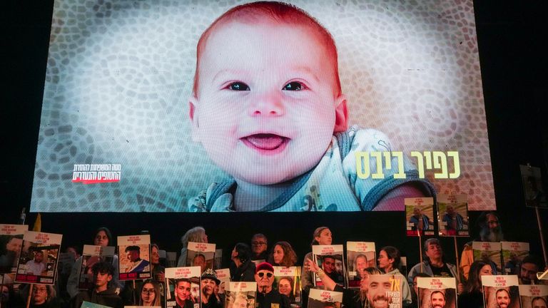 Demonstrators hold portraits of hostages held by Hamas in the Gaza Strip as a video featuring Kfir Bibas, who, along with his parents Shiri and Yarden Bibas, and his brother Ariel, is still being held hostage in Gaza, plays behind them during a protest in Tel Aviv, Israel, Saturday Jan. 18, 2025. (AP Photo/Ohad Zwigenberg)