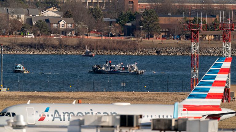 Police and coast guard boats are seen around a wreckage site in the Potomac River as an American Airlines plane passes in the foreground at Ronald Reagan Washington National Airport, Saturday, Feb. 1, 2025, in Arlington, Va., (AP Photo/Jose Luis Magana)
