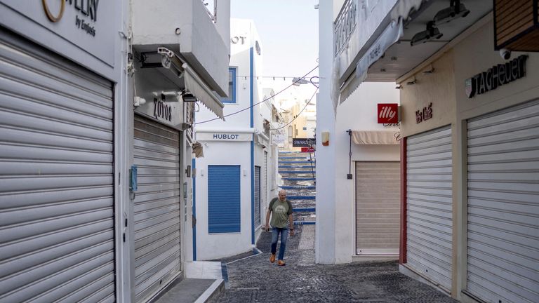 A man walks between closed tourist shops in Santorini.
Pic: Reuters