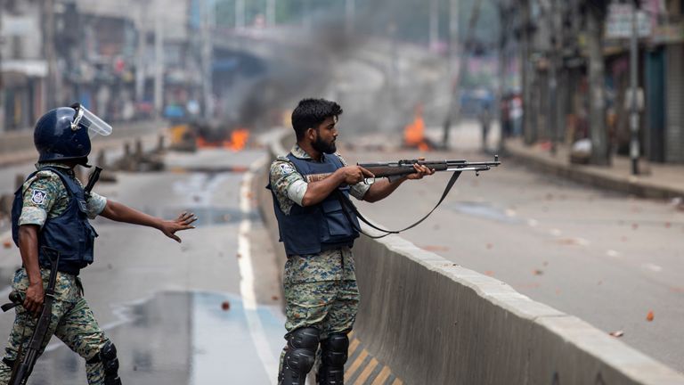 A policeman aims his weapon at protesters during an imposed curfew on 5 August.
Pic: Reuters/Rajib Dhar