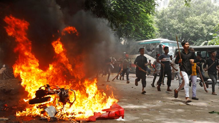 People run past a vehicle set on fire by protesters during a rally against Ms Hasina.
Pic: Reuters/Rajib Dhar