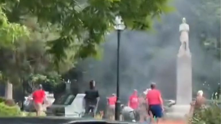 Smoke rises over a park area in Boulder as people look on